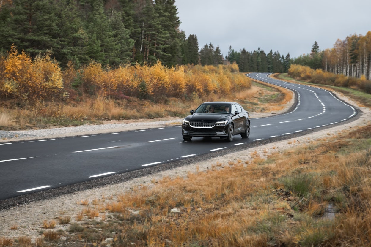 Black Polestar 2 prototype on a forest road in autumn.