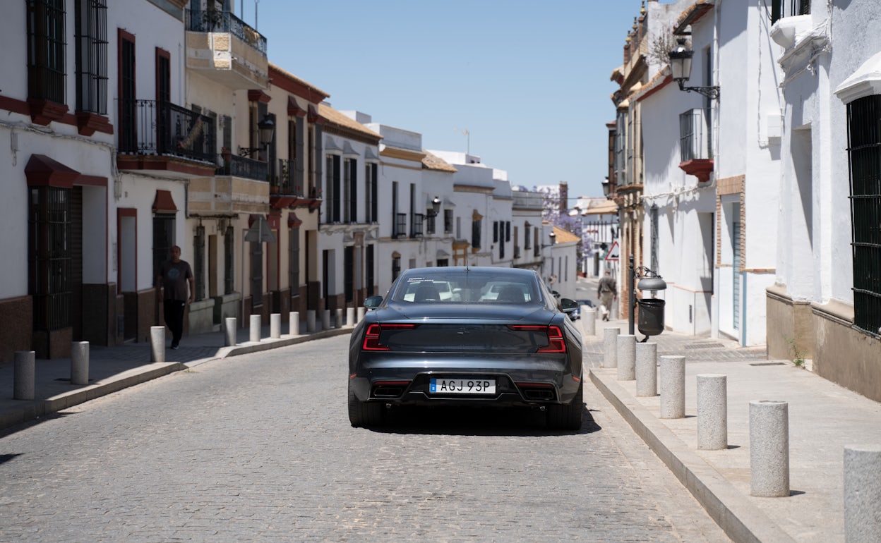 The back of a Polestar 1 in the colour Black Midnight driving on a village road.