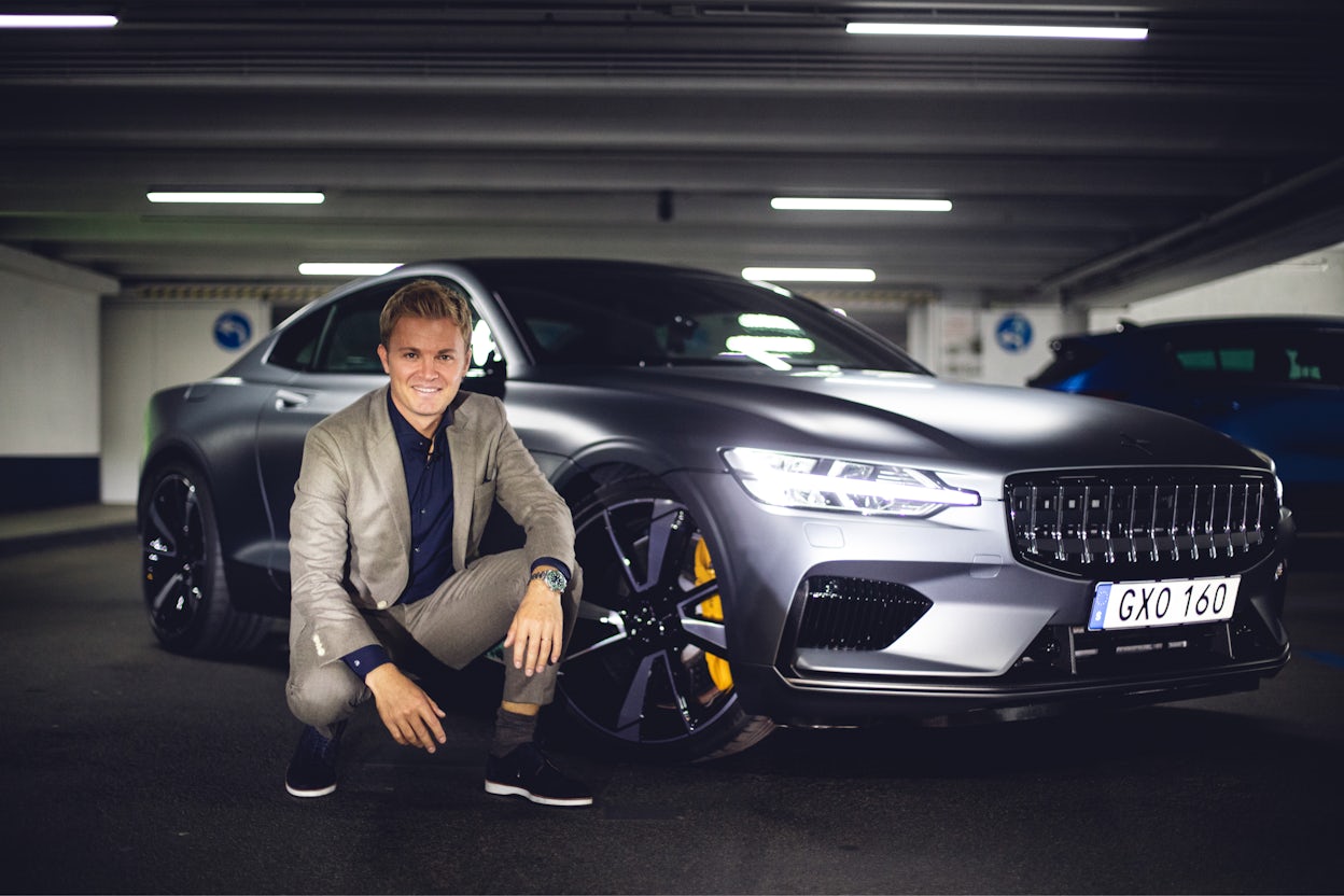 Nico Rosberg squats next to a metallic Polestar 1.