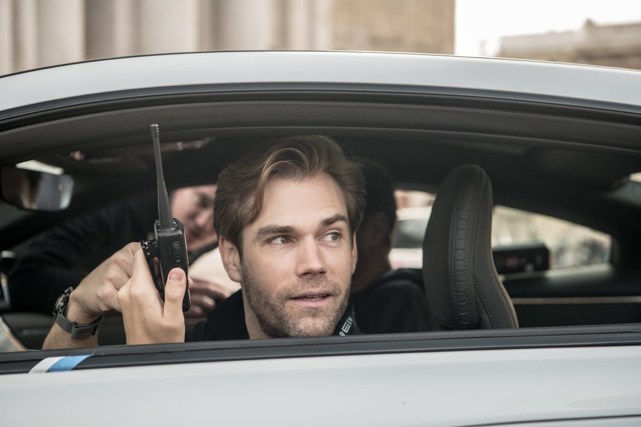 A person holding a walkie talkie sitting in a Polestar at the 1000 Miglia.