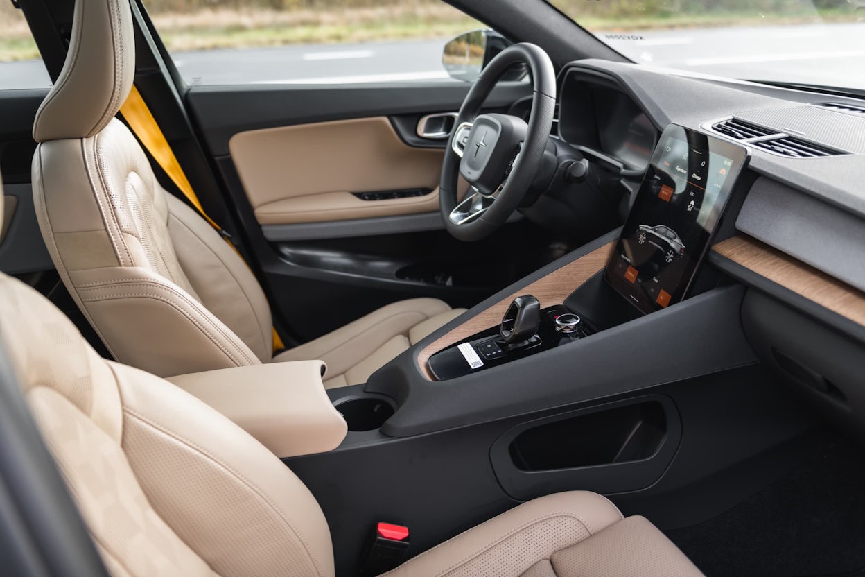 Interior in a Polestar 2 showing beige leather seats and wooden trims.