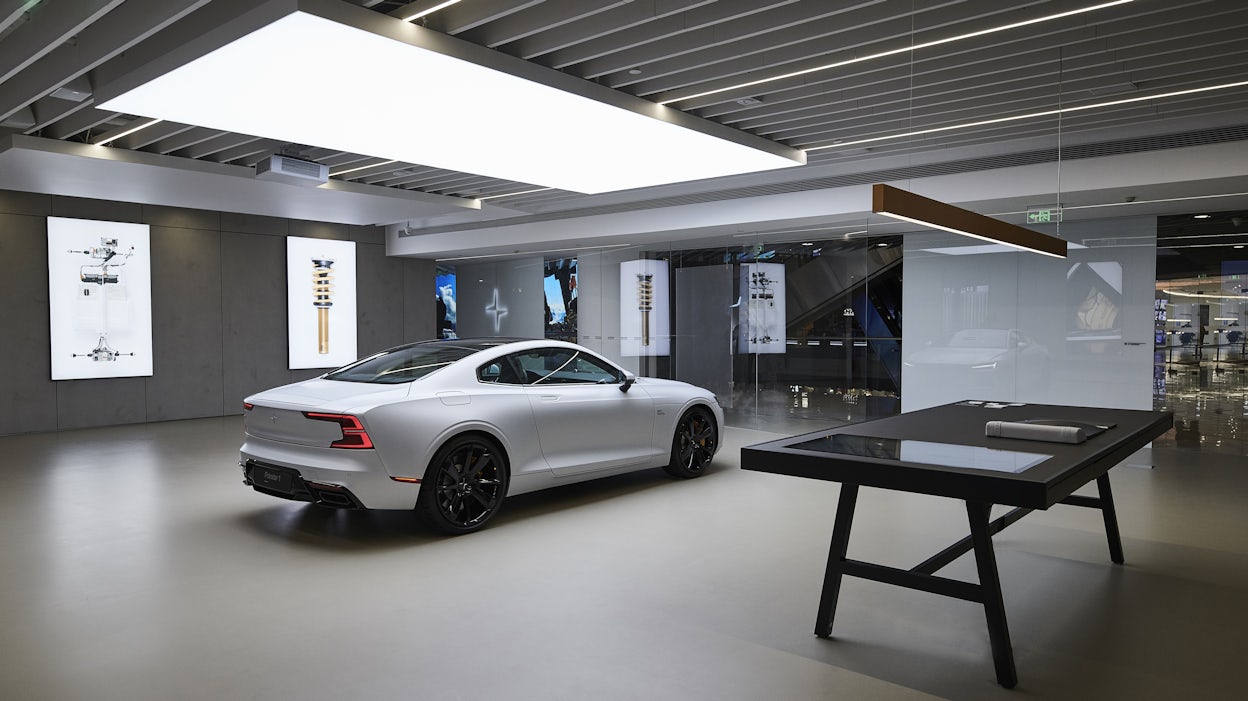 White Polestar 1 displayed in a grey, minimalistic retail space with glass walls.