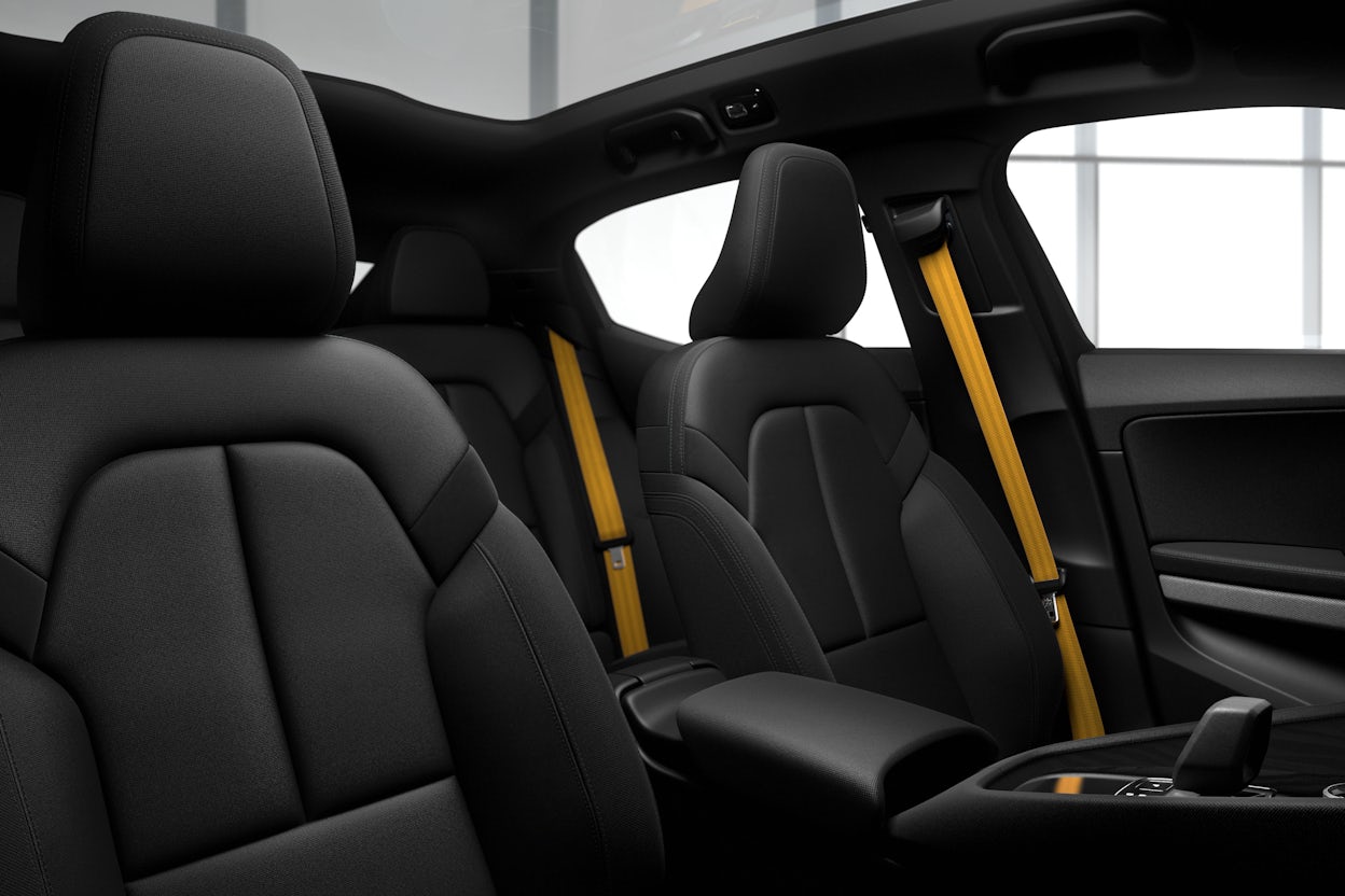 Black front seats of a Polestar 2 with the stereotypical Polestar golden seat belts.