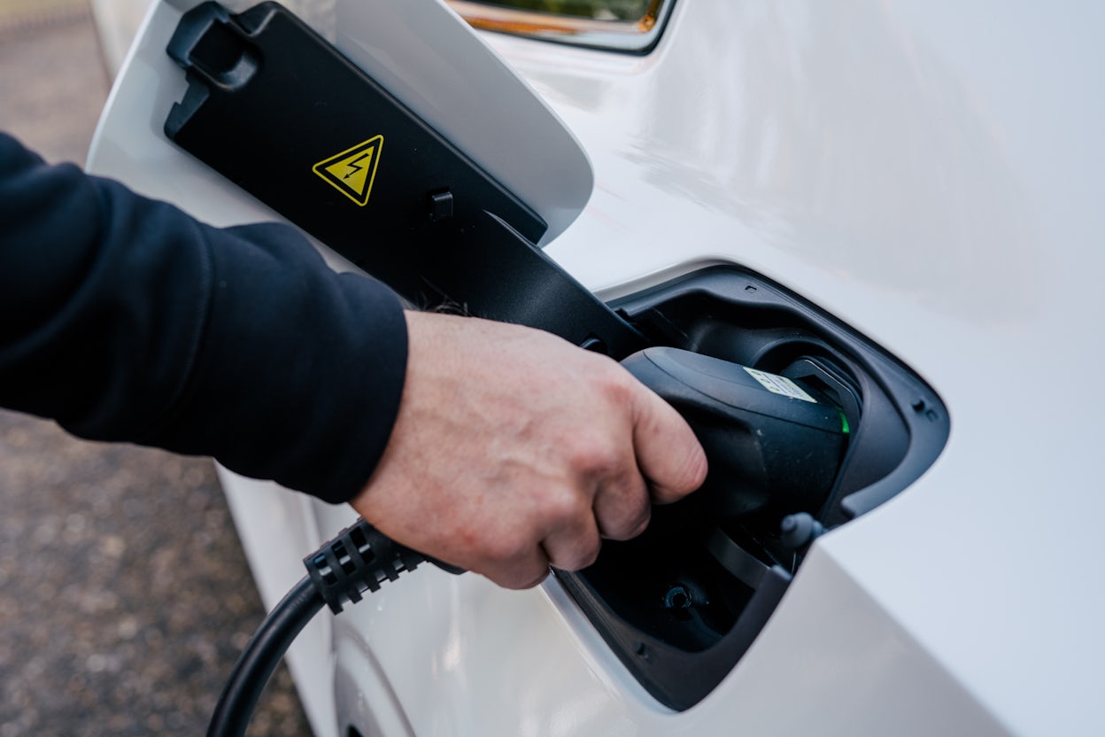 Close-up of a hand holding the charging cable while charging a car.