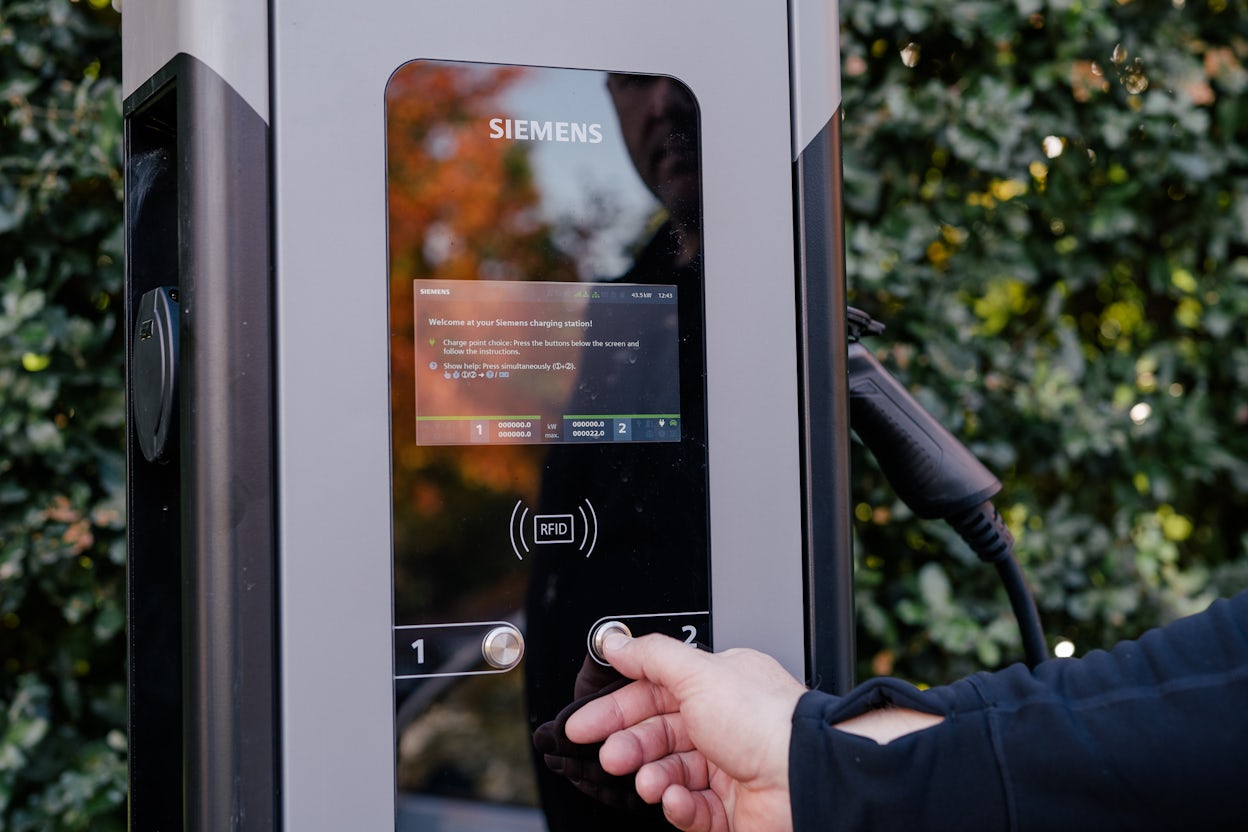 Hand pushing a button on a Siemens charging station.