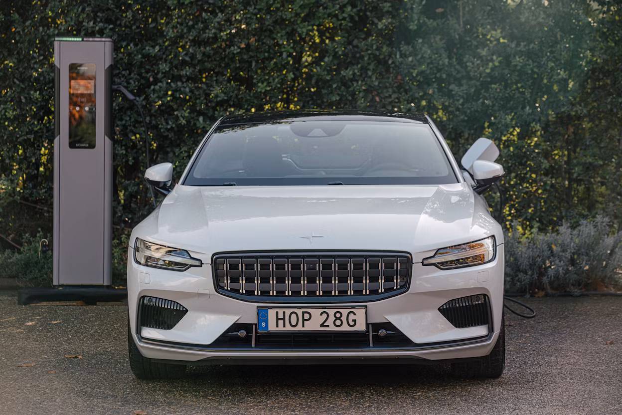 A white Polestar 1 parked next to a Siemens charging station with the charging cable connected.