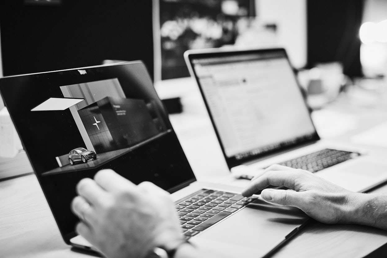 Hands by a laptop displaying the image of a Polestar.