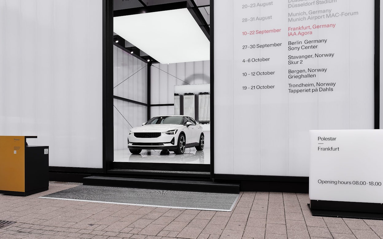 A white Polestar 2 in a pop-up exhibition display that reads Polestar Frankfurt.