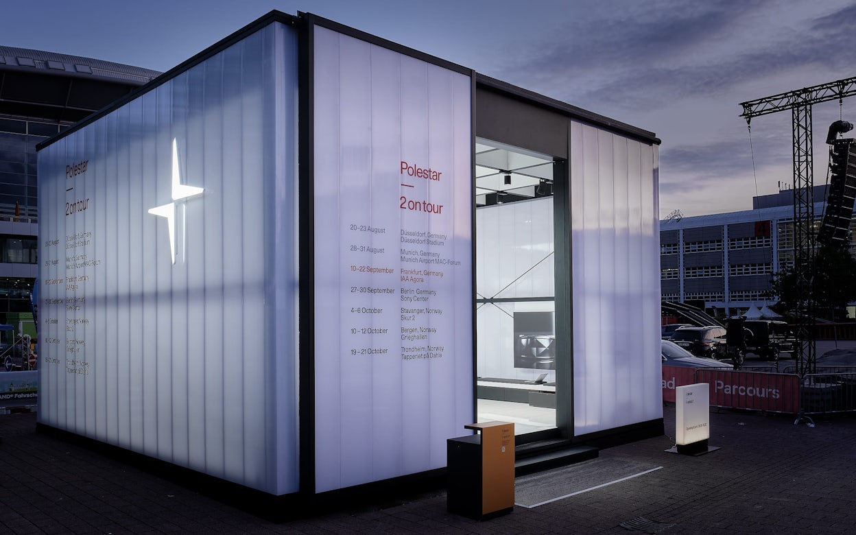 A white Polestar 2 pop-up exhibition display with the Polestar logo and the words Polestar 2 on tour.