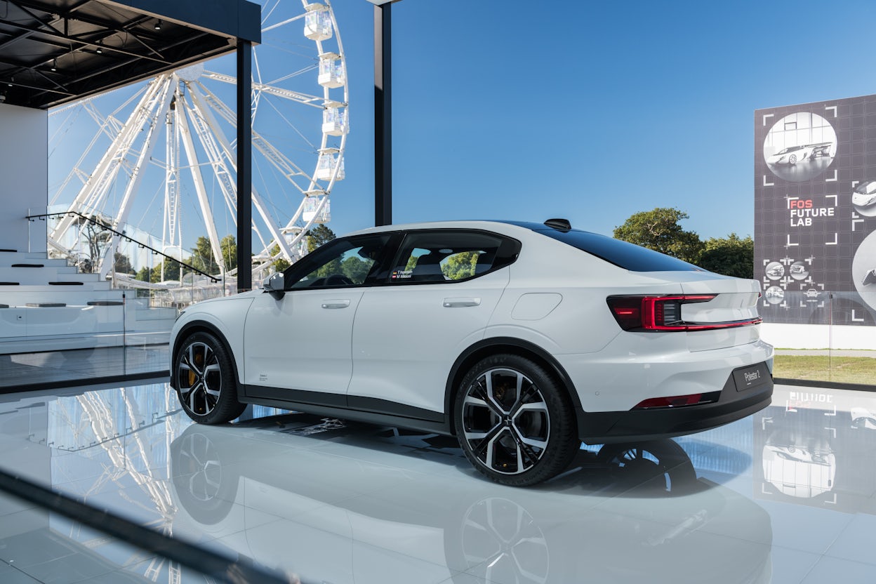 White Polestar 2 showcased in a spacious exhibition area, with a Ferris wheel visible through the window.