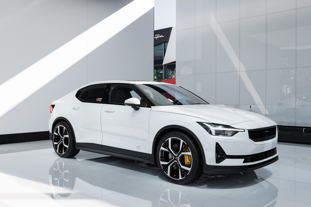 White Polestar 2 displayed in a sleek, modern exhibition space with pristine white walls and polished flooring.