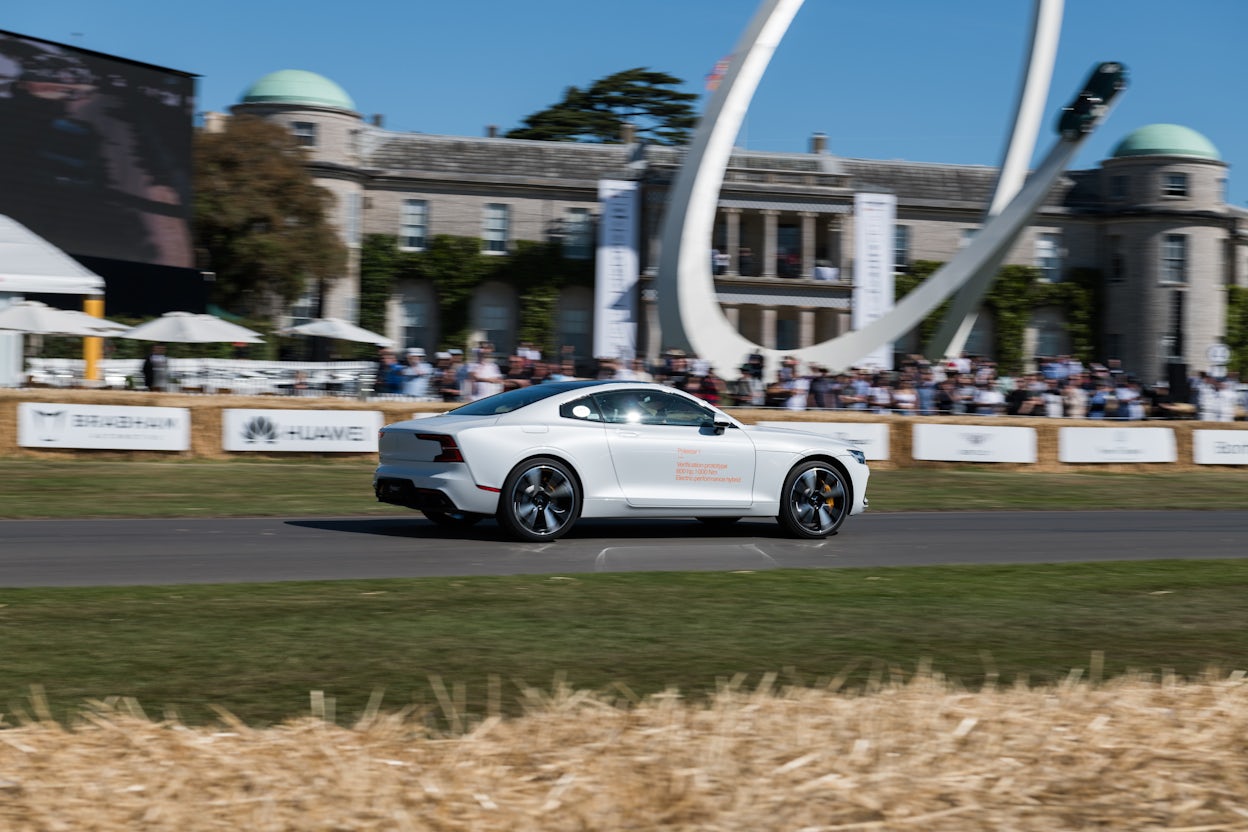 White Polestar 1 racing on the track while spectators observe from the sidelines.