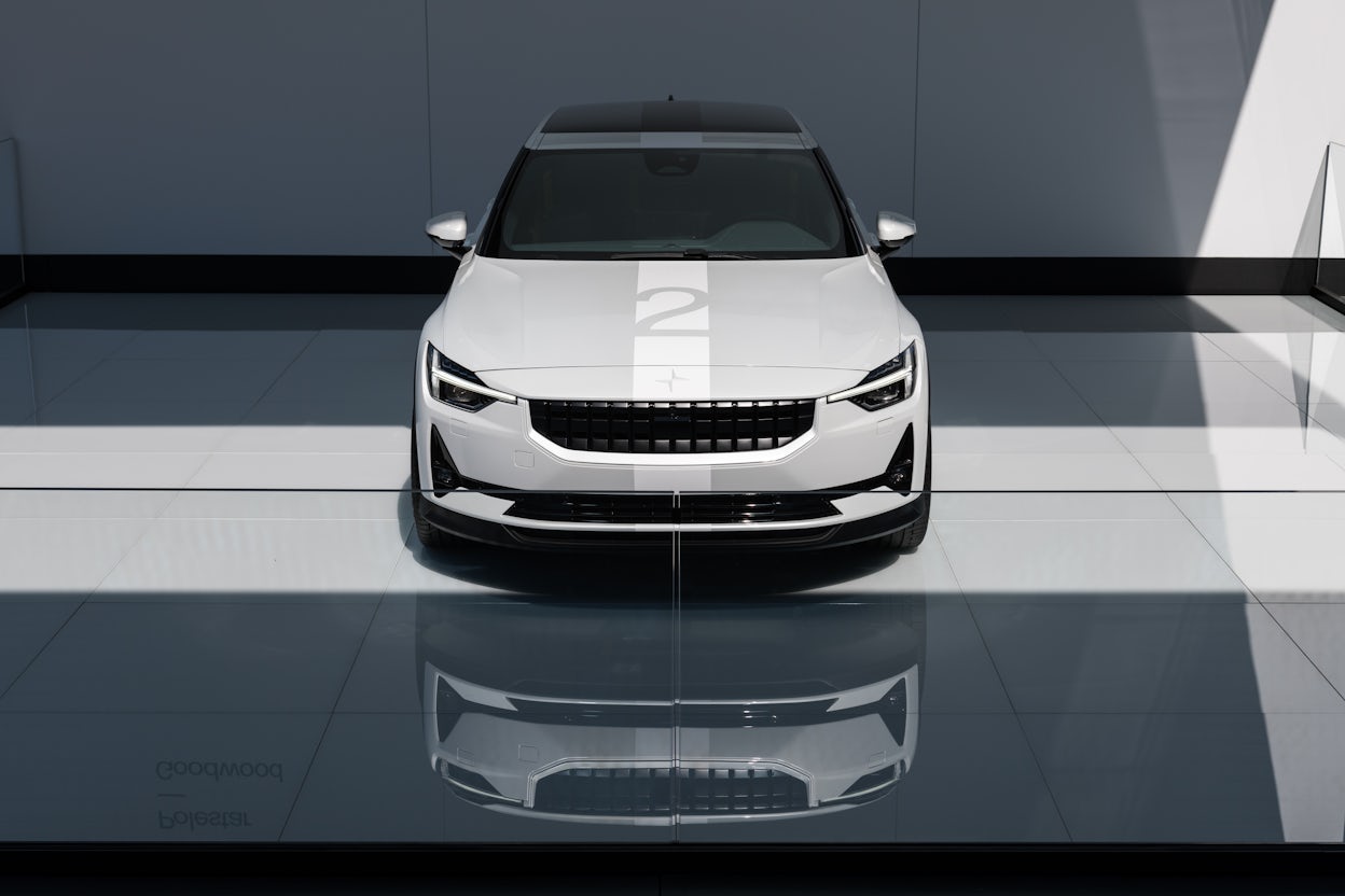 Front view of a white Polestar 2 in a modern exhibition space with white walls and polished flooring.