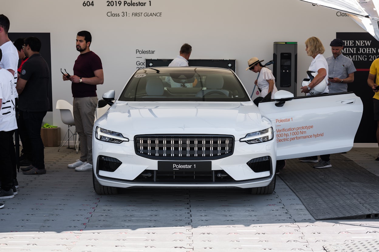 Front view of a white Polestar 1 at the Goodwood Festival of Speed with a group of people inspecting the car.
