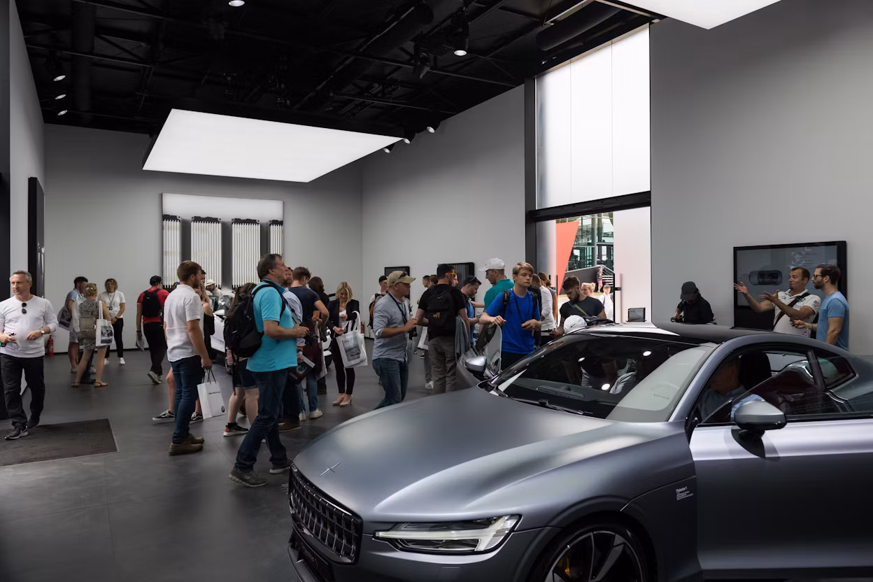 Visitors gathered around a metallic Polestar 1 showcased in a exhibition space at the Goodwood Festival.