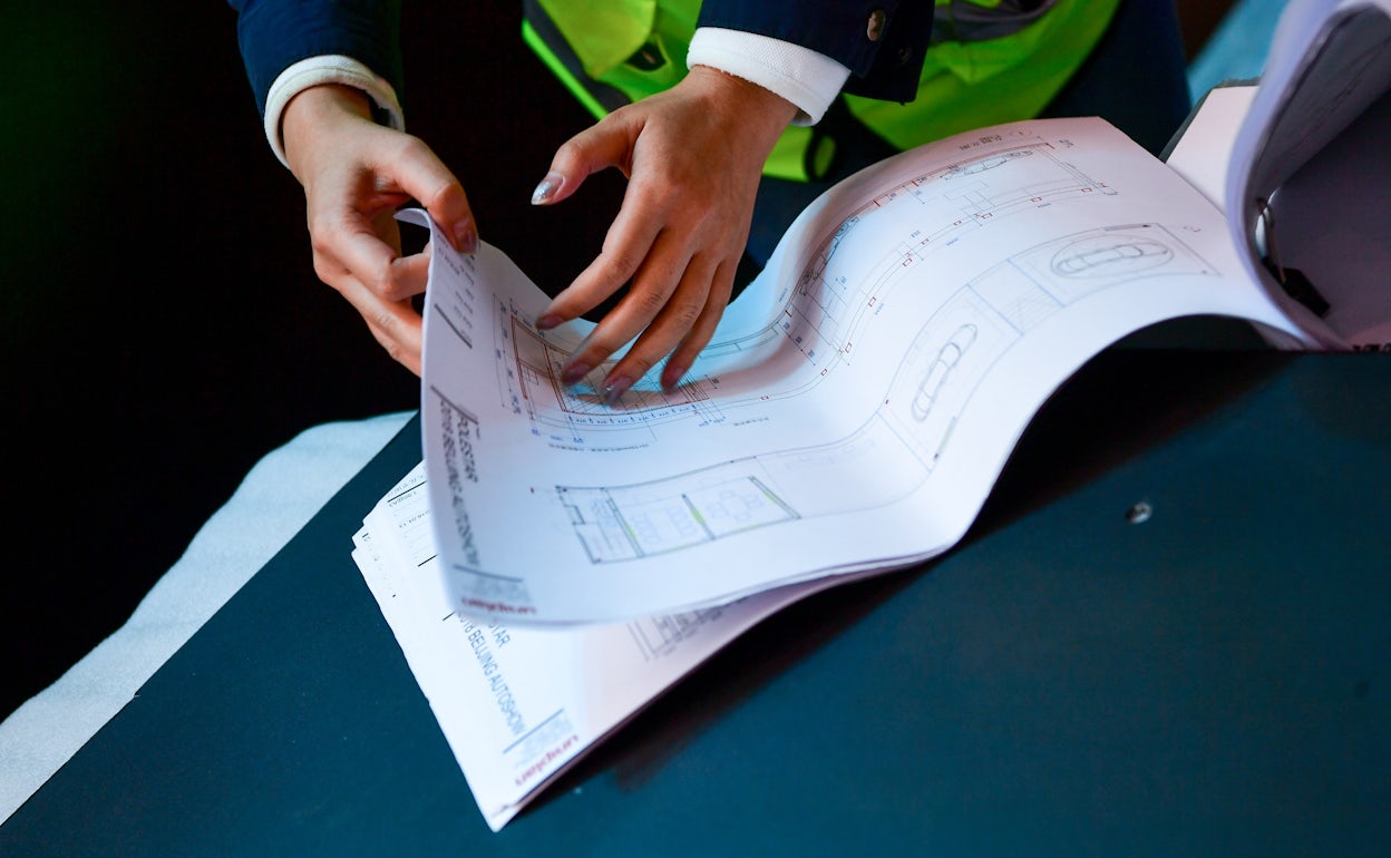 A person flipping through the pages of the construction drawing for the Polestar display.