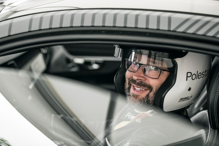 Joakim Rydholm sitting in the front seat wearing a white racing helmet.