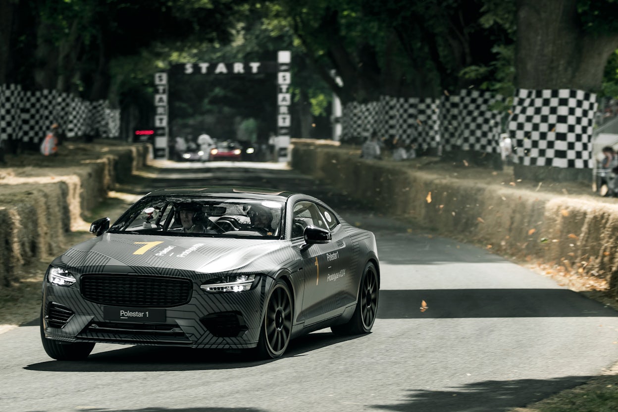 Front view of a grey Polestar 1 driving on a race track.