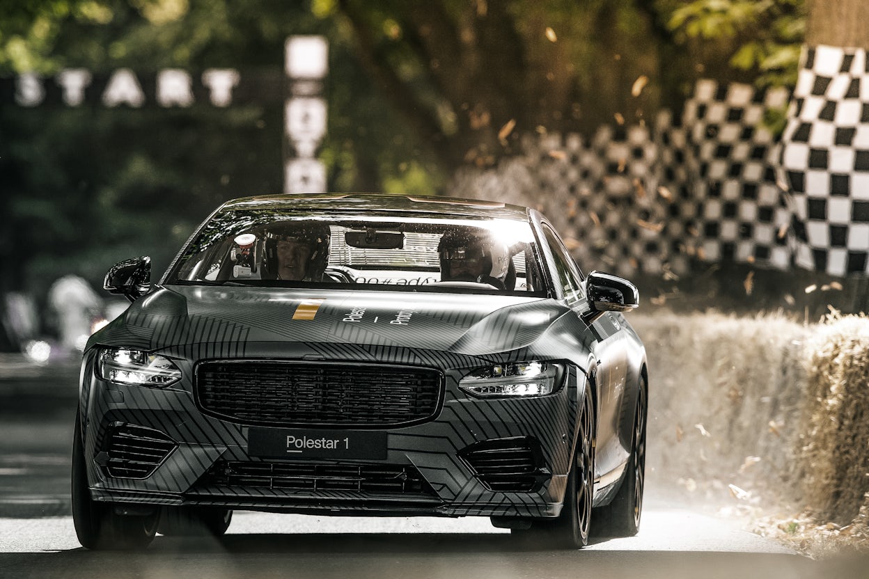 A Polestar 1 driving on a race track with two people visible in the front seat.