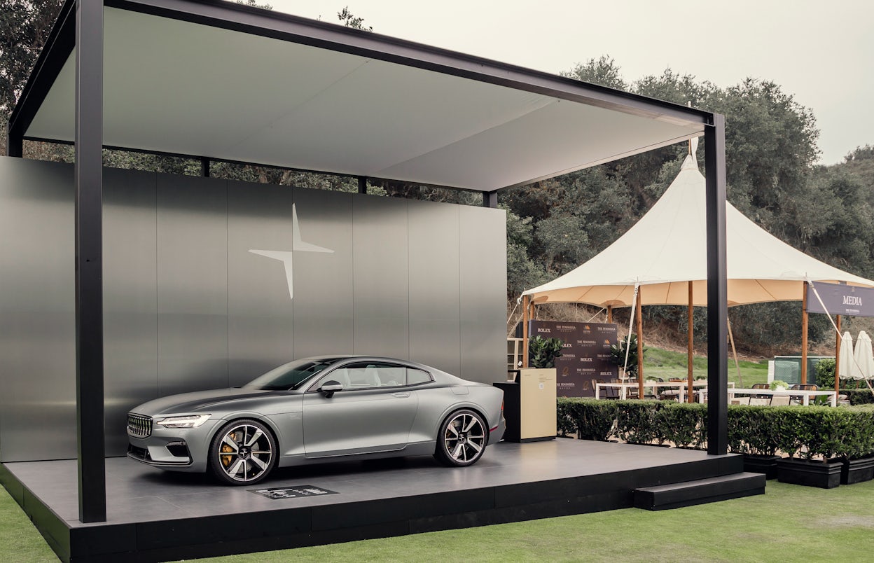 A silver Polestar 1 in a pop-up exhibition display next to a café tent.