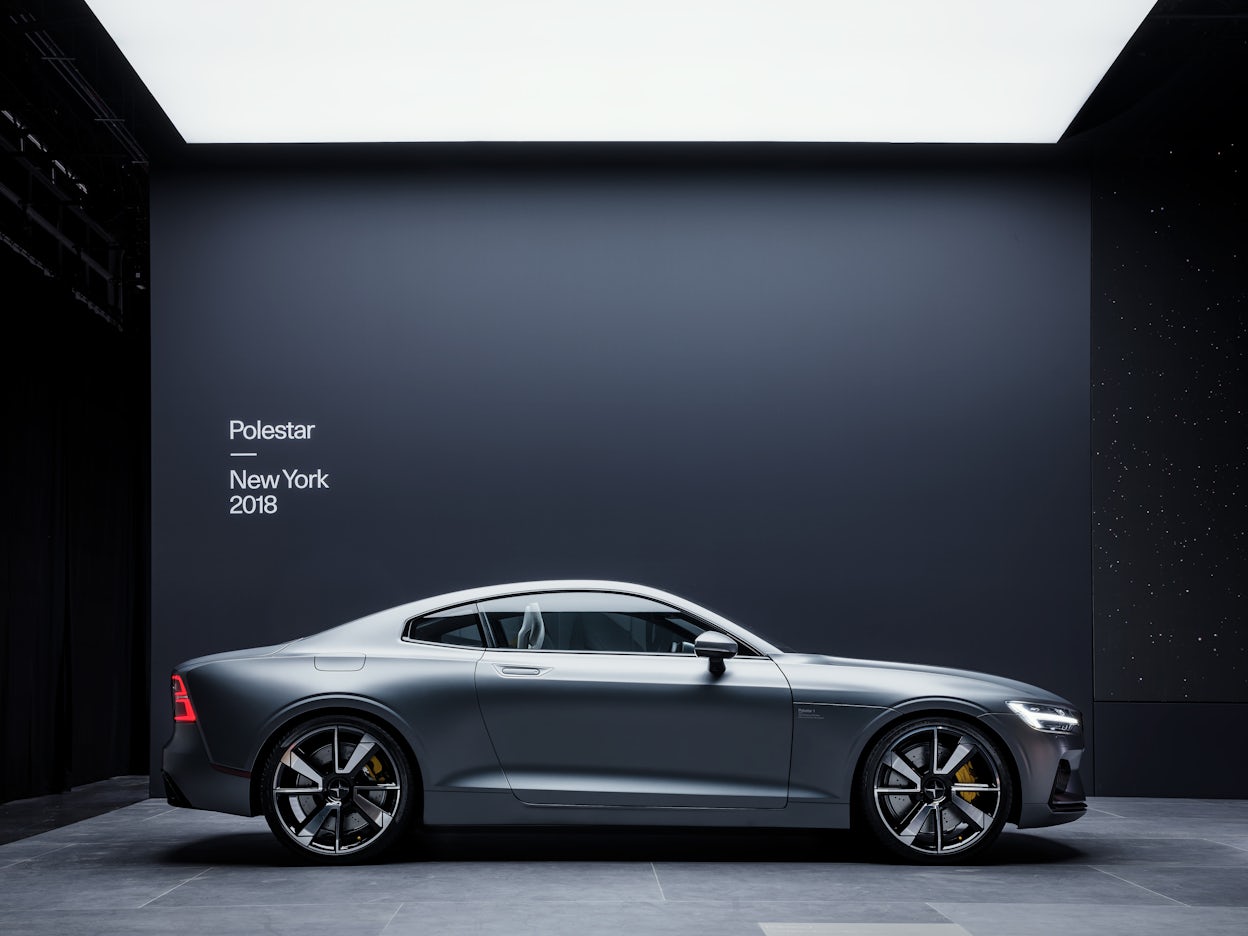 A silver Polestar 1 on display in front of a black wall with the text Polestar New York 2018.