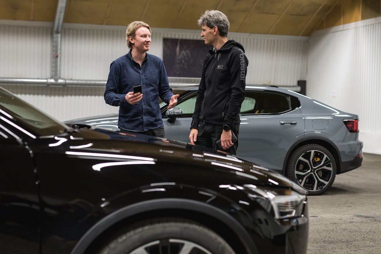 Two men talking between two parked Polestar car in a garage.