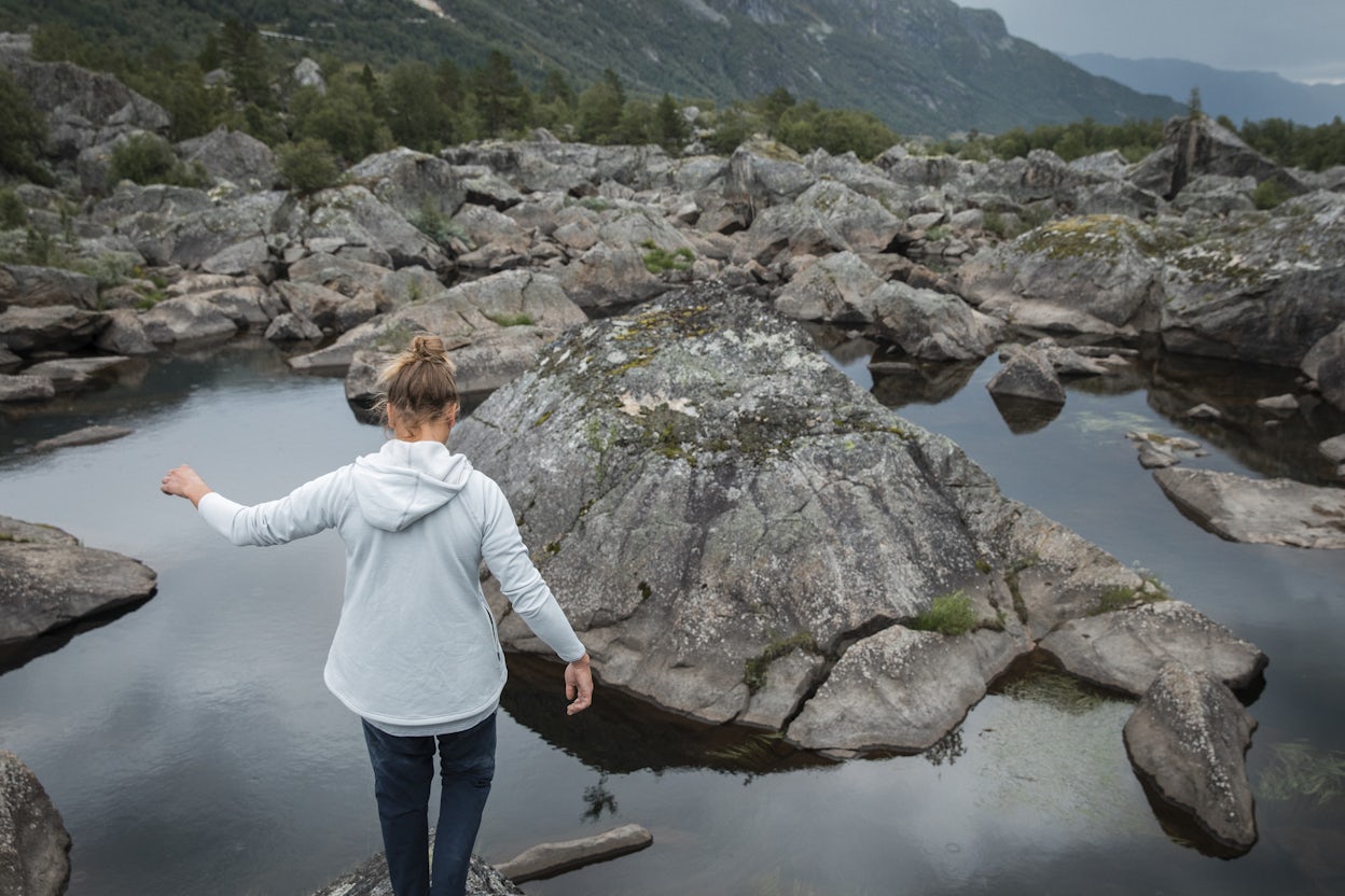 Back view of a person balancing on a rock in a pond.