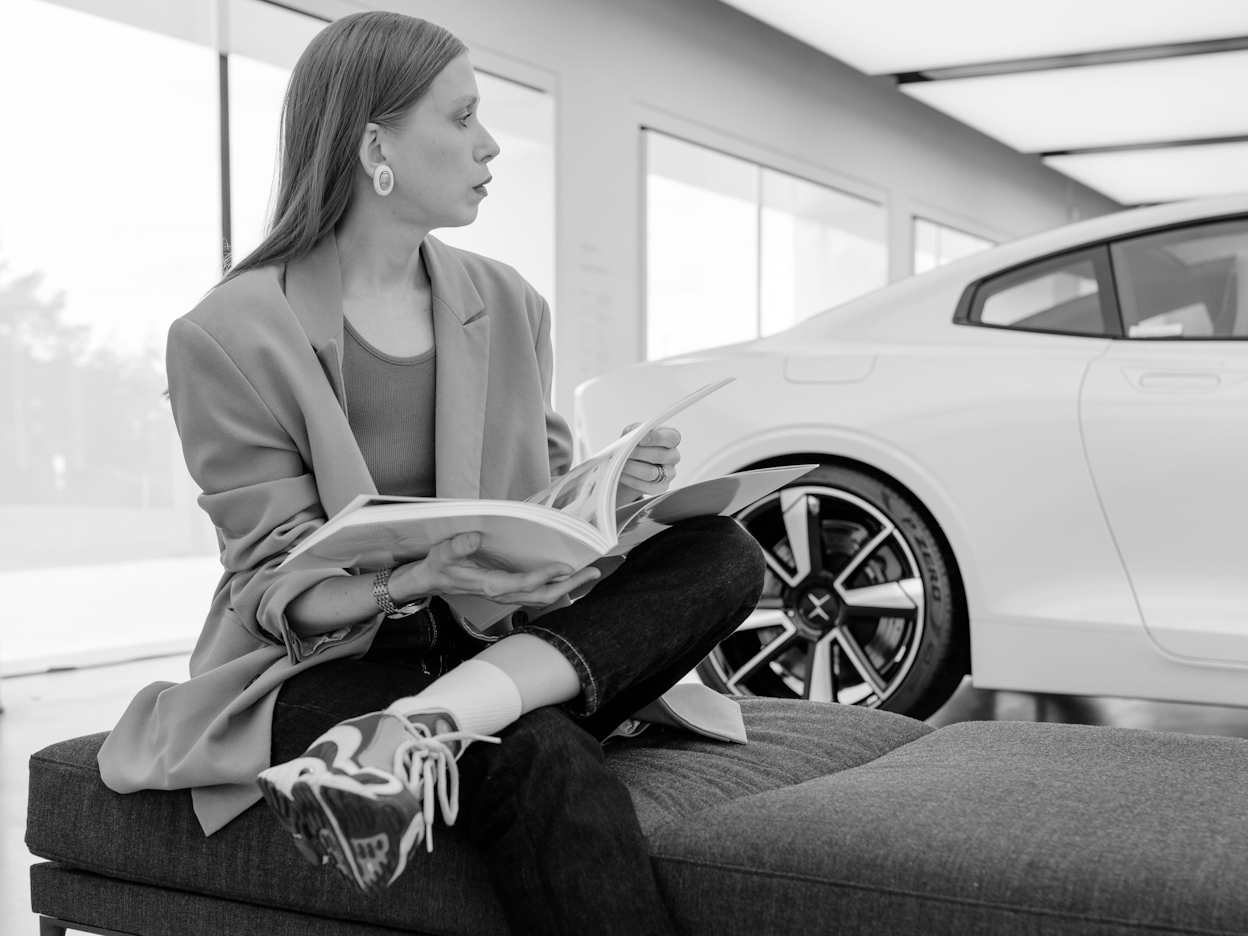 Jenny Mustard sitting in front of a Polestar photographed in black and white.