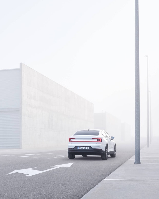 White Polestar 2 driving by a building in a gloomy environment