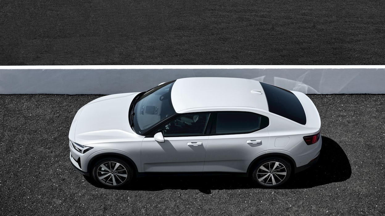 Bird's-eye view of a white Polestar 2 parked next to a low white wall.