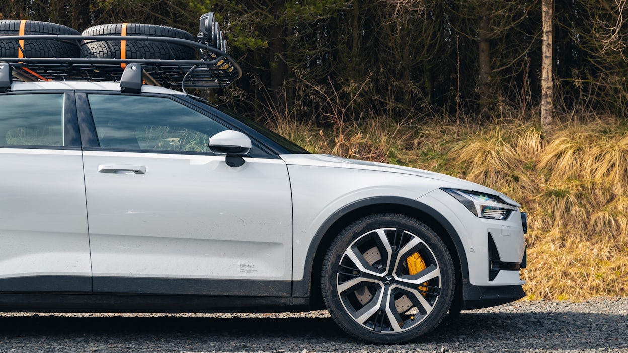 White Polestar 2 with a roof rack parked in nature.