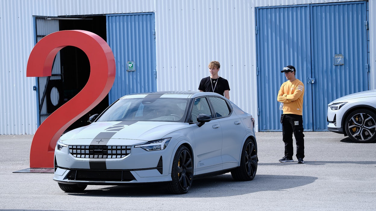Polestar 2 parked in front of a garage with two men inspecting it from behind.