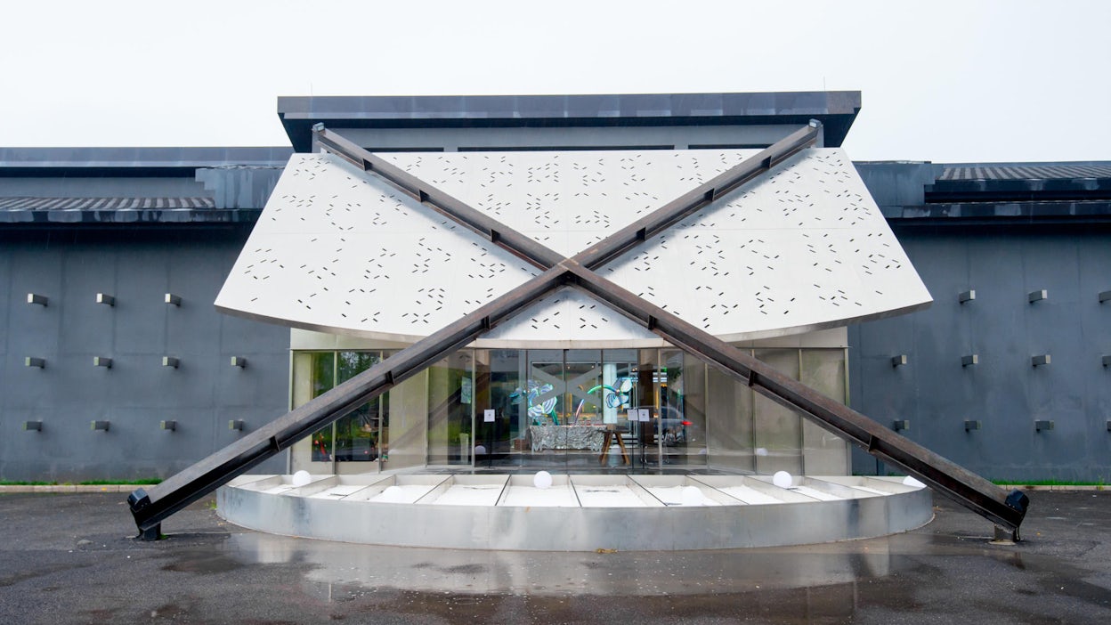 Front view of an artsy building with a big X covering the entrance.