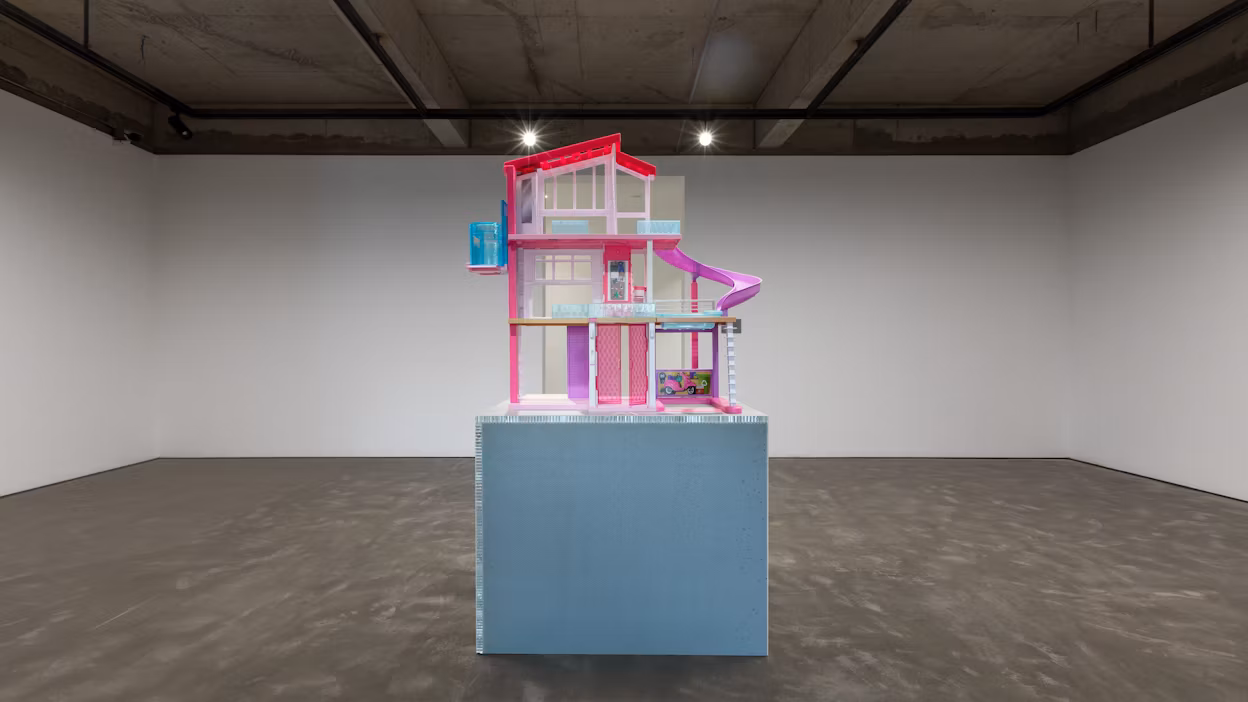 Pink and purple barbie house displayed in an empty industrial room.
