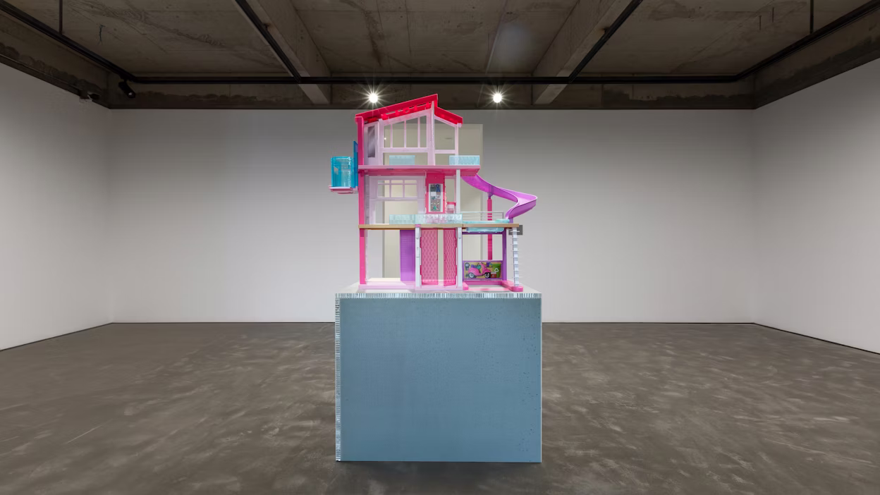 Pink and purple barbie house displayed in an empty industrial room.