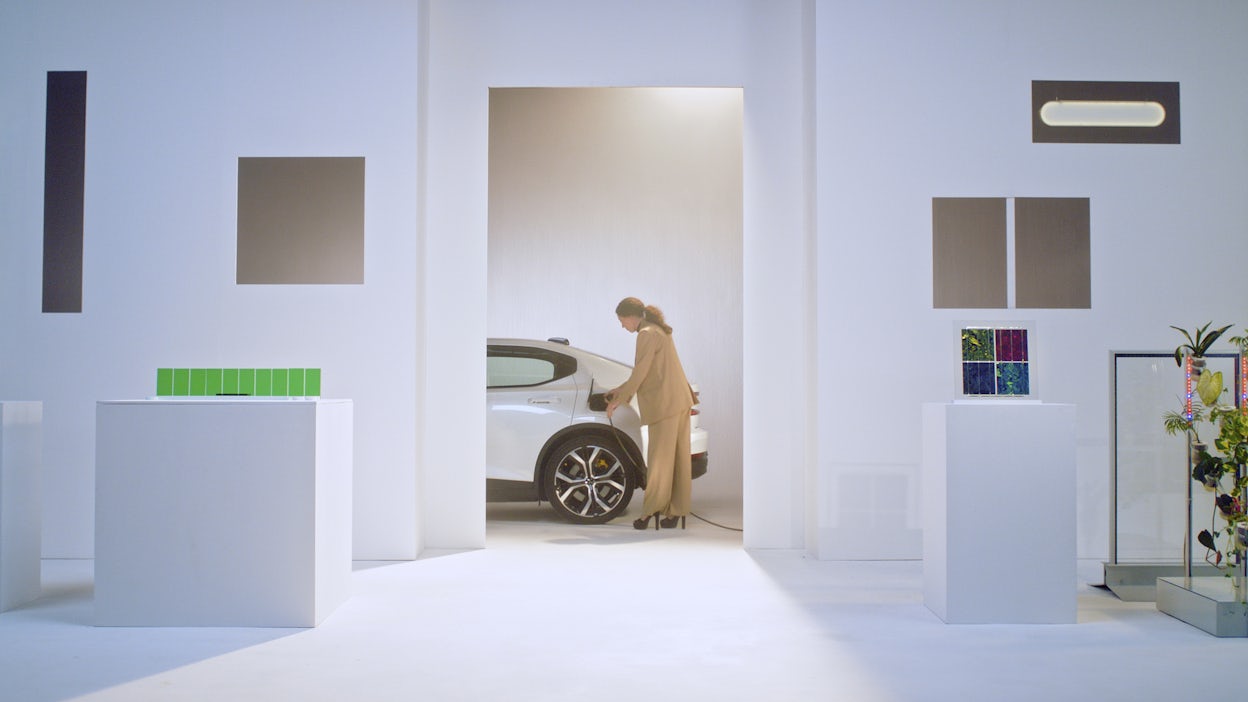 Woman standing next to a Polestar and plugging in the charger.