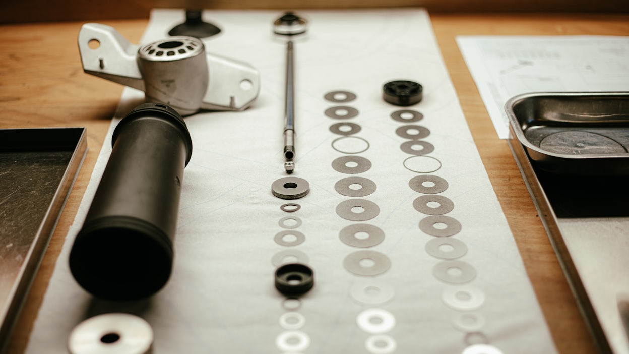 Components of the Öhlins Polestar 2 damper placed on a wooden table.