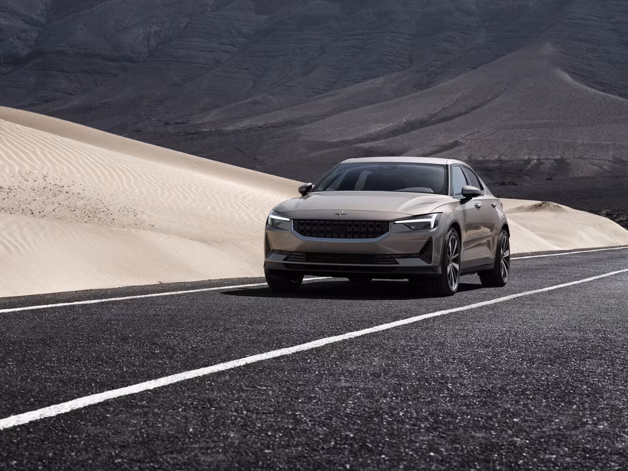 Beige Polestar 2 driving on road in a desert landscape