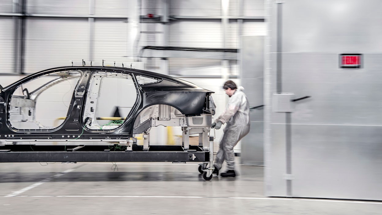 Worker dragging the bonded aluminium unibody of Polestar 5 in a workshop.