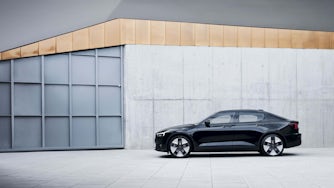 Image of a black Polestar 2 in front of a grey building. 
