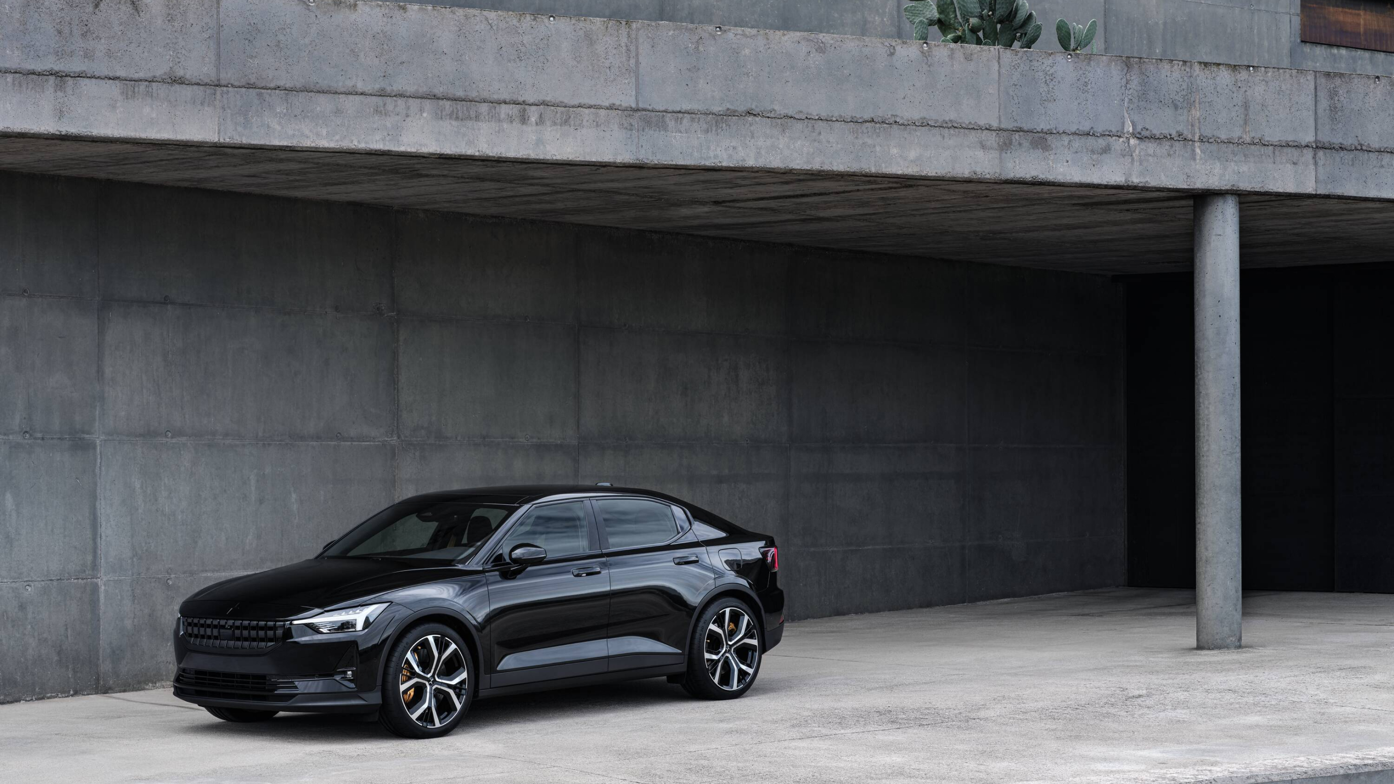 Black Polestar 2 parked against a cement-like building