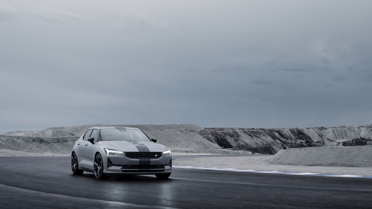 A Polestar 2 driving on a track near a quarry. 