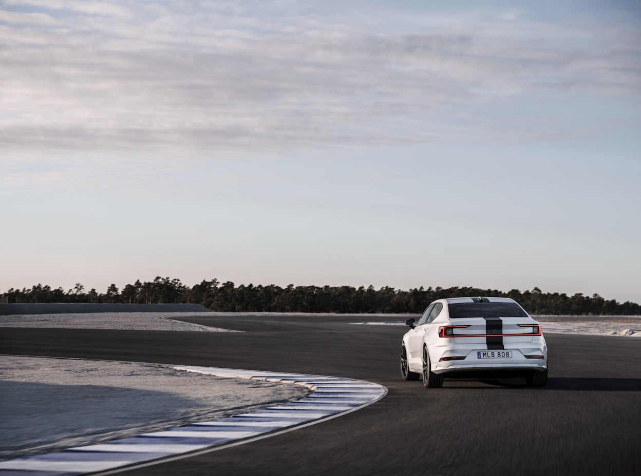 A Polestar 2 driving on a track near a quarry. 