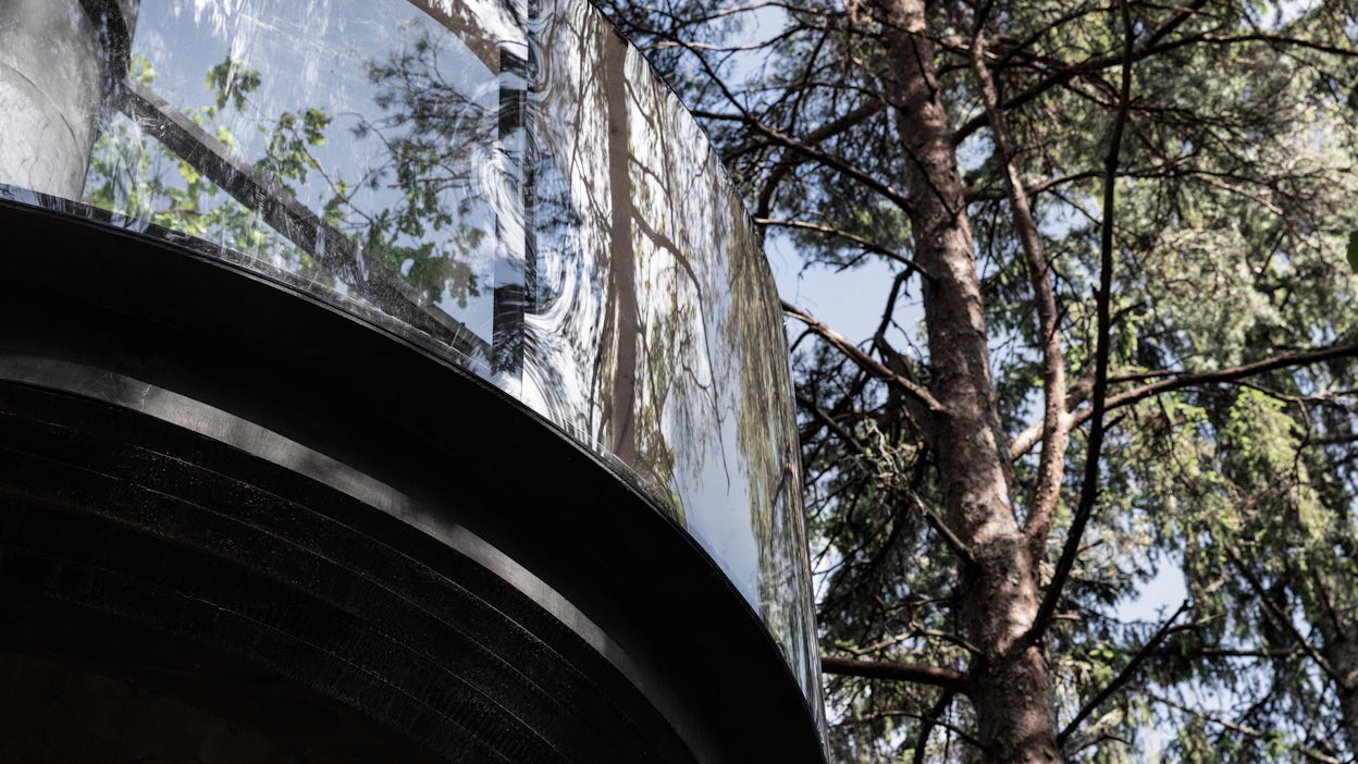 The large windows of a black treehouse.