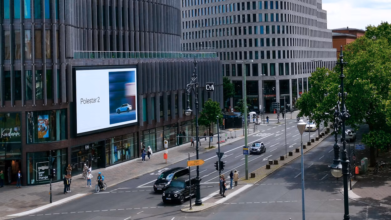 Polestar 2 digital billboard on a city building with cars driving next to it.