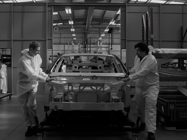 Two men on the assembly line with the body work of Polestar Precept.