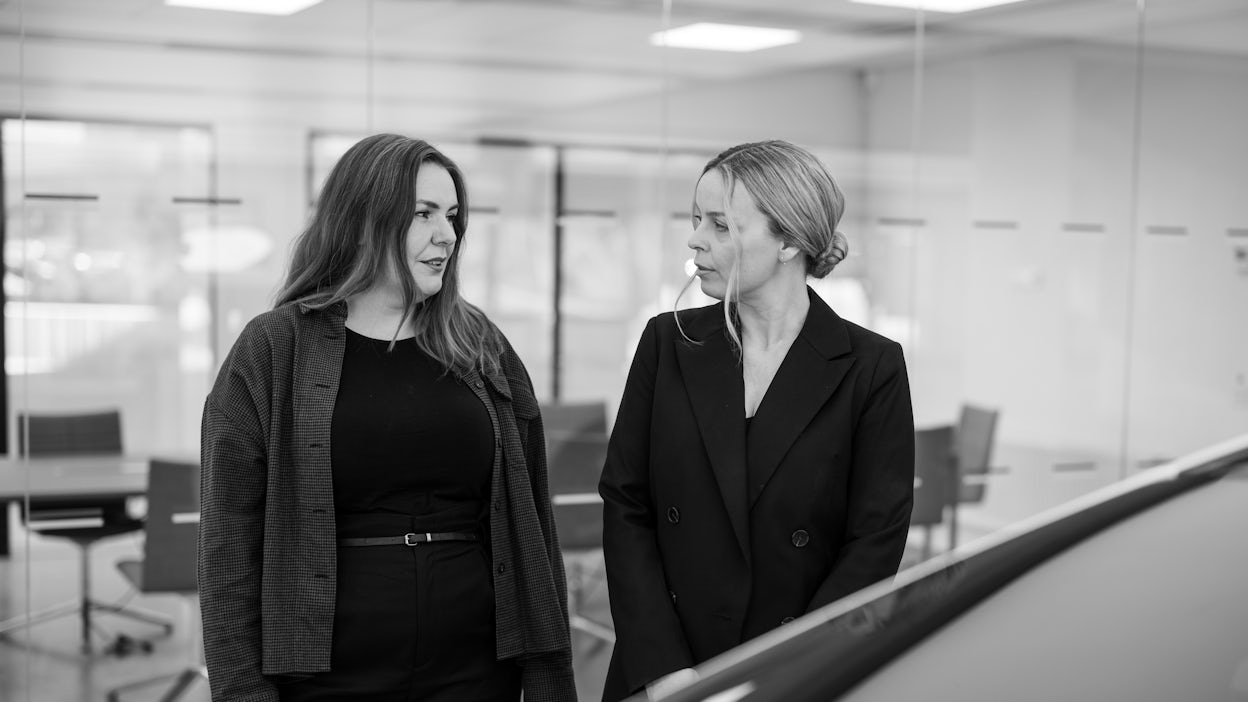 Fredrika Klarén speaking to a woman outside an office meeting room.