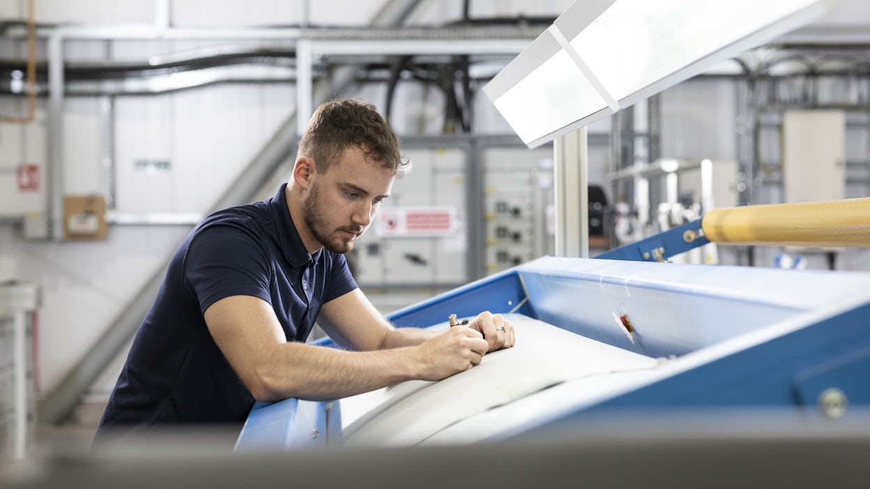 Man cutting out a piece of leather inside a production factory.