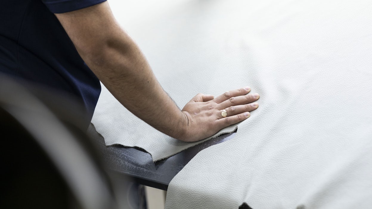 A man's hand placed on a large piece of leather.