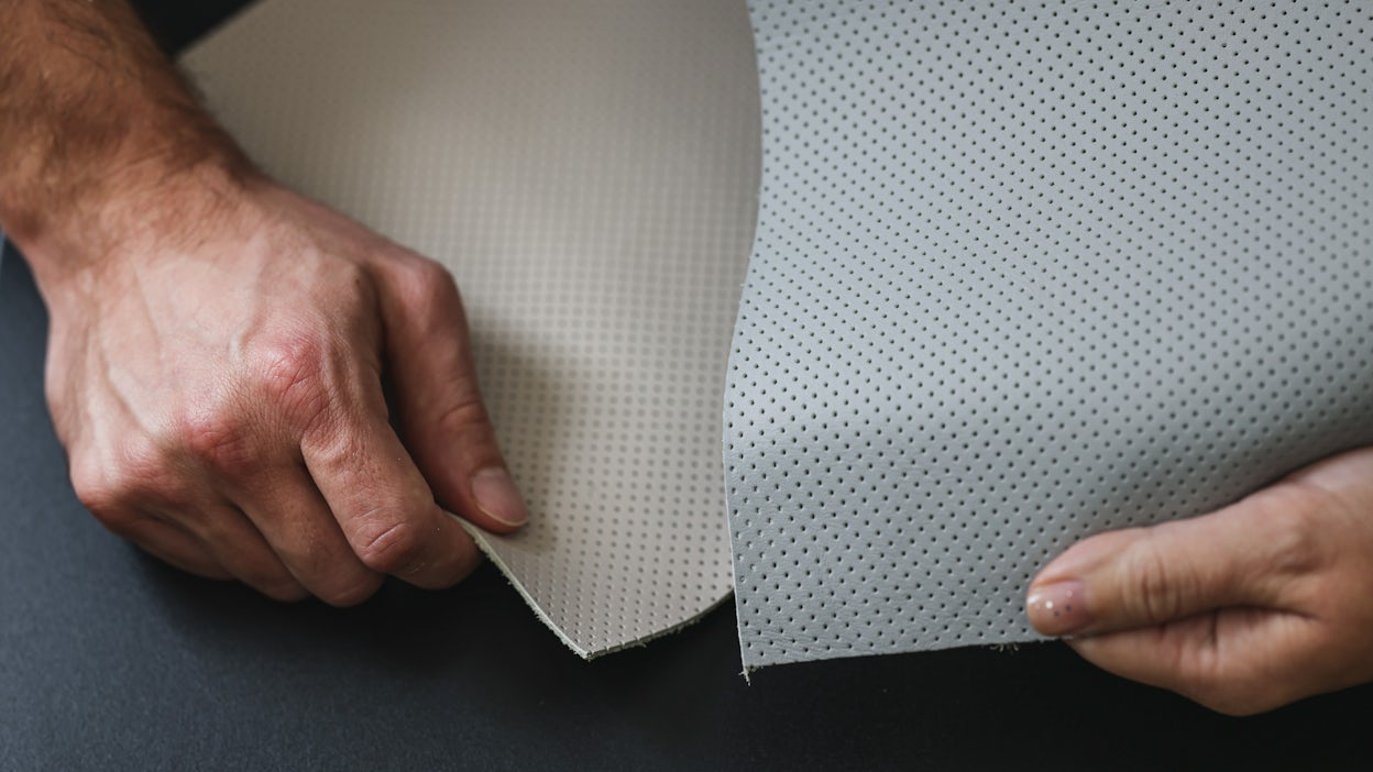 Two hands holding leather samples.